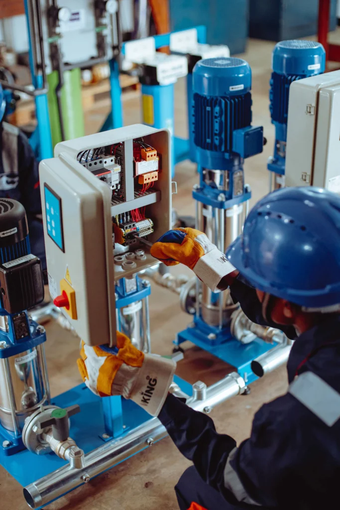 Técnico trabajando en un tablero eléctrico junto a equipos de bombeo